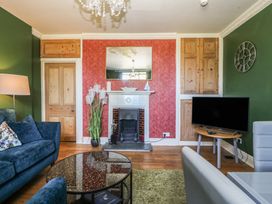 A living room with a sofa, table, and television at Mallards Rest in Llandwrog near Bontnewydd, Gwynedd