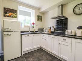 A kitchen with a refrigerator, sink, microwave, and cabinets at Mallards Rest in Llandwrog near Bontnewydd, Gwynedd