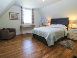 A bedroom with a bed, nightstand, and chair at Mallards Rest in Llandwrog near Bontnewydd, Gwynedd
