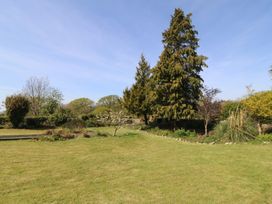 A garden with grass, trees, and flower beds at Mallards Rest in Llandwrog near Bontnewydd, Gwynedd