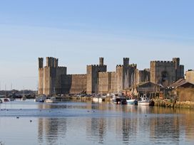 A castle by the water with boats at Caernarfon Castle in Caernarfon