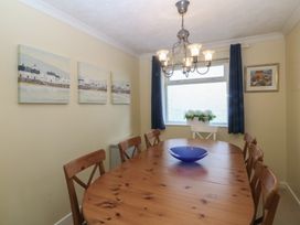 A dining room with a wooden table and paintings at Wingelock in Rhosneigr
