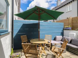 An outdoor seating area with a table, chairs, and an umbrella at Wingelock in Rhosneigr