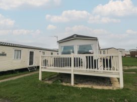 A mobile home with a white railing deck and green grass around at No30 Elm Rise in Gristhorpe near Filey