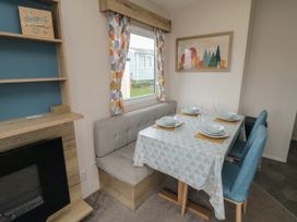 A dining area with a table set for four near a window with patterned curtains at No30 Elm Rise in Gristhorpe near Filey