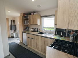 A kitchen with wooden cabinets a window a sink a gas stove a toaster and various kitchen utensils at No30 Elm Rise in Gristhorpe near Filey