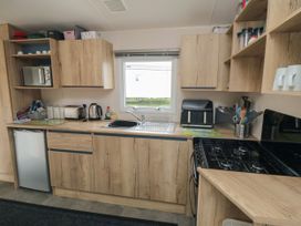 A kitchen with wooden cabinets a window a stove a sink and various kitchen appliances at No30 Elm Rise Gristhorpe near Filey
