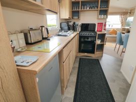A kitchen with wooden cabinets stove kettle toaster and sink at No30 Elm Rise Gristhorpe near Filey