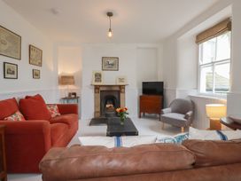A living room with a sofa, armchair, coffee table, and fireplace at 84 Fore Street