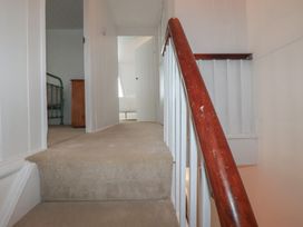 A staircase leading to a hallway with a bed and doorway at 84 Fore Street 