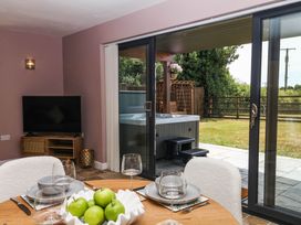 A dining room with a table set for meals and a hot tub visible through sliding glass doors at Harescombe Lodge Morchard Bishop