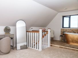 A bathroom with a bathtub and a mirror at Harescombe Lodge in Morchard Bishop