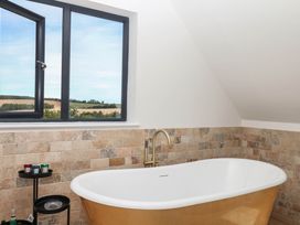 A bathroom with a bathtub near a window at Harescombe Lodge Morchard Bishop