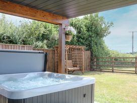 A hot tub and swing seat in a garden at Harescombe Lodge Morchard Bishop