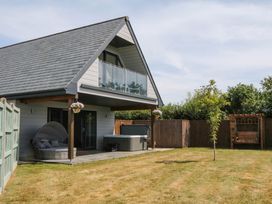 A house with a balcony and hot tub in the garden at Harescombe Lodge Morchard Bishop