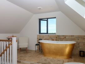 A bathroom with a bathtub and a chair at Harescombe Lodge in Morchard Bishop