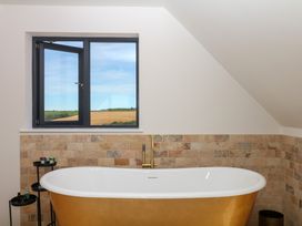 A bathroom with a bathtub and window at Harescombe Lodge in Morchard Bishop