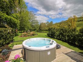 A hot tub on a deck surrounded by greenery at Pultheley Cottage Hyssington near Churchstoke