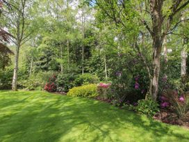 A garden with grass, trees, and flower bushes at Pultheley Cottage Hyssington near Churchstoke