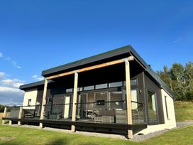 A house with a deck and glass railing at Osprey View Lodge & Hot Tub Aberfeldy