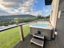 An outdoor area with a hot tub and drinks overlooking a mountain view at Osprey View Lodge & Hot Tub in Aberfeldy