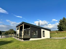 A lodge with a balcony and large windows at Osprey View Lodge & Hot Tub Aberfeldy