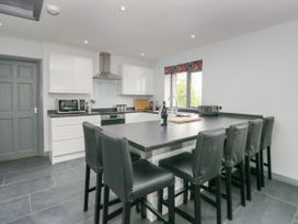 A kitchen with bar stools and appliances at Fell View Cottage in Lambrigg near Kendal
