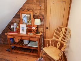 A hallway with a table, chair, mirror and lamp at Bruno's Bothy Middleton near Belford