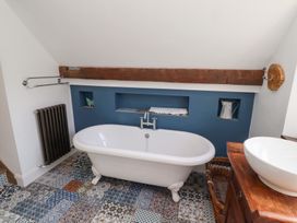 A bathroom with a bathtub and vanity sink at Bruno's Bothy Middleton near Belford