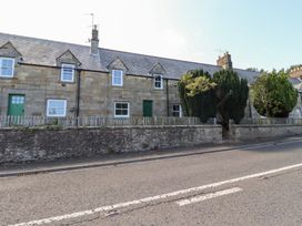 A stone cottage with green doors and windows near the road at Kits Cottage Middleton near Belford