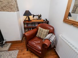A snug with an armchair and a bookcase at Kits Cottage Middleton near Belford