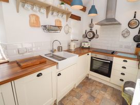 A kitchen with a sink, oven, and appliances at Kits Cottage in Middleton near Belford