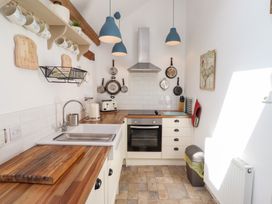 A kitchen with a sink, oven, and shelf at Kits Cottage in Middleton near Belford