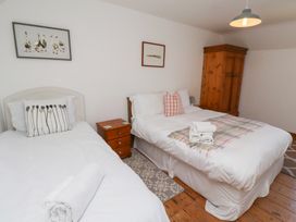 A bedroom with two beds and side tables at Kits Cottage in Middleton near Belford