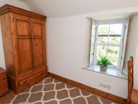 A bedroom with a wardrobe and window at Kits Cottage Middleton near Belford