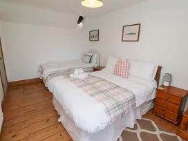 A bedroom with two beds and a bedside table at Kits Cottage Middleton near Belford