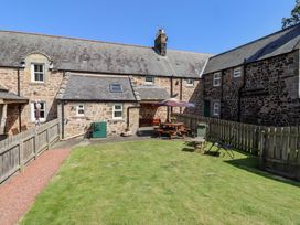A garden with grass and patio furniture at Kits Cottage in Middleton near Belford