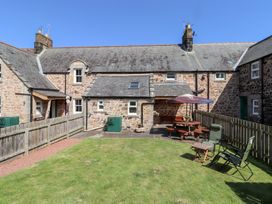A garden with a table and chairs at Kits Cottage Middleton near Belford