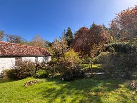 A garden with a cottage, trees, and bushes at Laundry Cottage in Clovelly