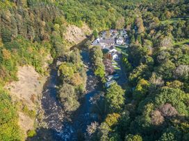 An aerial view of houses beside a river and surrounding forest at Apartment 3 in Keswick