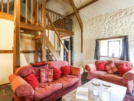 A living room with two sofas and a wooden staircase at Thatched Cottage in Llanybydder