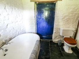 A bathroom with a bathtub toilet and a blue door at Thatched Cottage in Llanybydder