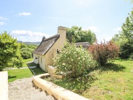 A thatched cottage with stone steps and surrounding greenery at Thatched Cottage in Llanybydder