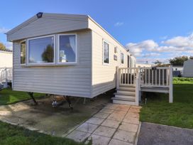 An exterior view of a beige static caravan with steps leading to a deck at HD Retreat in Tattershall
