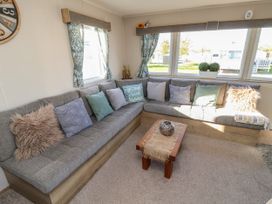 A living room with a gray sectional sofa and various cushions around a small wooden coffee table at HD Retreat in Tattershall