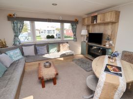A living room with a grey L shaped sofa cushions wooden coffee table television and dining table at HD Retreat in Tattershall