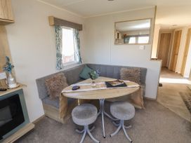 A dining area with corner bench seating table and two stools in a small living space at HD Retreat in Tattershall