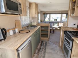 A kitchen with a microwave kettle and toaster overlooking a sitting area with sofa and coffee table at HD Retreat in Tattershall