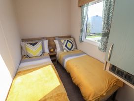 A small bedroom with two single beds with yellow blankets and patterned pillows at HD Retreat in Tattershall