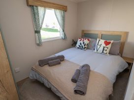 A bedroom with a bed towels on a blanket a window with curtains at HD Retreat in Tattershall